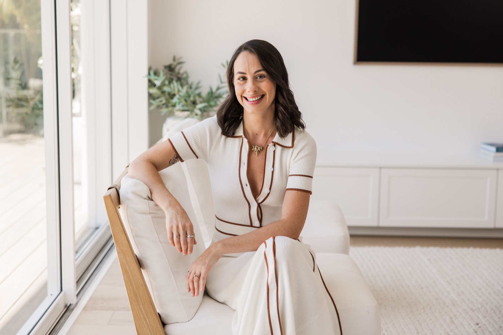 Gabi Saper laughing in a white armchair